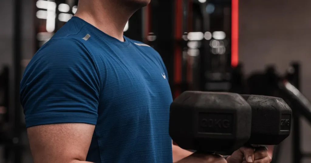 Homem levantando halteres em academia durante o treino