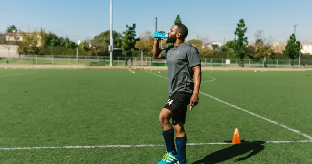 Jogador de futebol se hidratando durante treino em campo