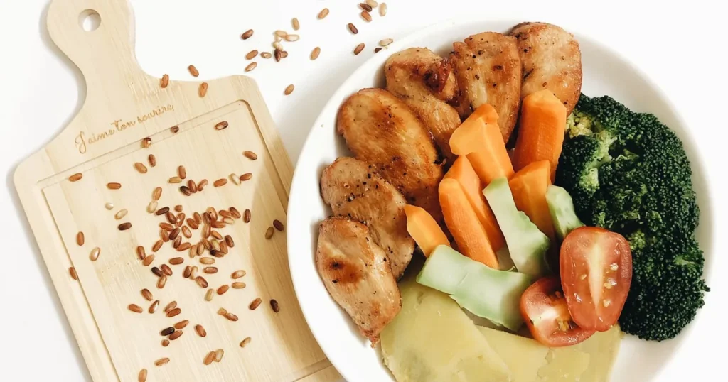 Prato com frango grelhado, brócolis, cenoura e tomate, visão de cima