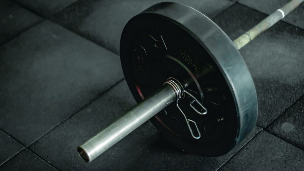 Barra de musculação carregada com anilhas no chão da academia