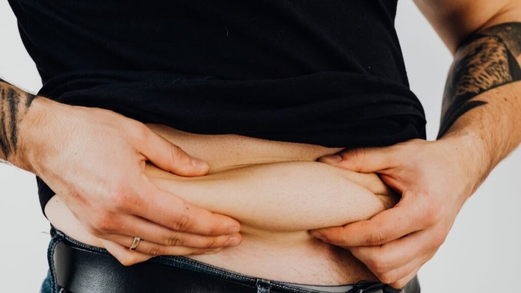 Homem fazendo o teste da pinça na gordura da barriga