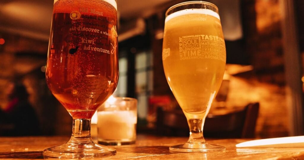 Dois copos de cerveja sobre uma mesa de madeira em um bar com luz quente