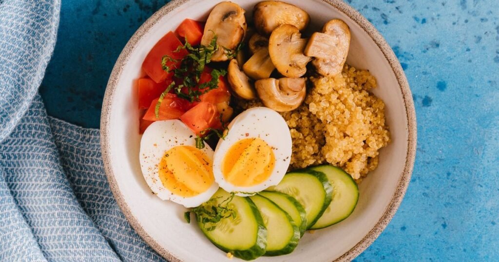 Vista de cima de uma tigela com ovo cozido, quinoa, tomate e pepino, uma refeição de recuperação depois de correr
